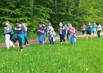 Teilnehmer der Barfußwanderung laufen barfuß durchs hohe Gras