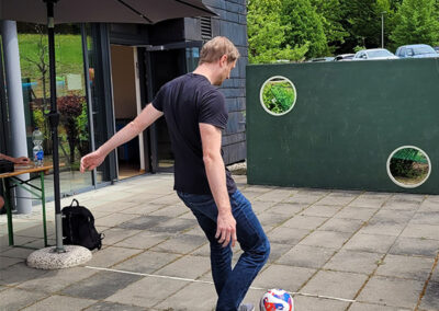 Ein Mann schießt mit einem Fußball auf eine Torwand